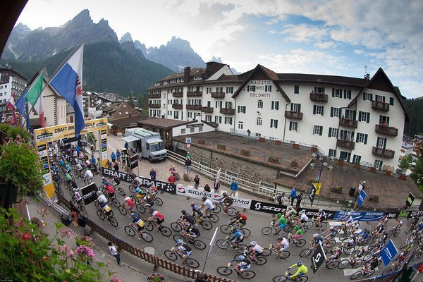 Ogromny peleton przejeżdża przez linię startu w San Martino di Castrozza